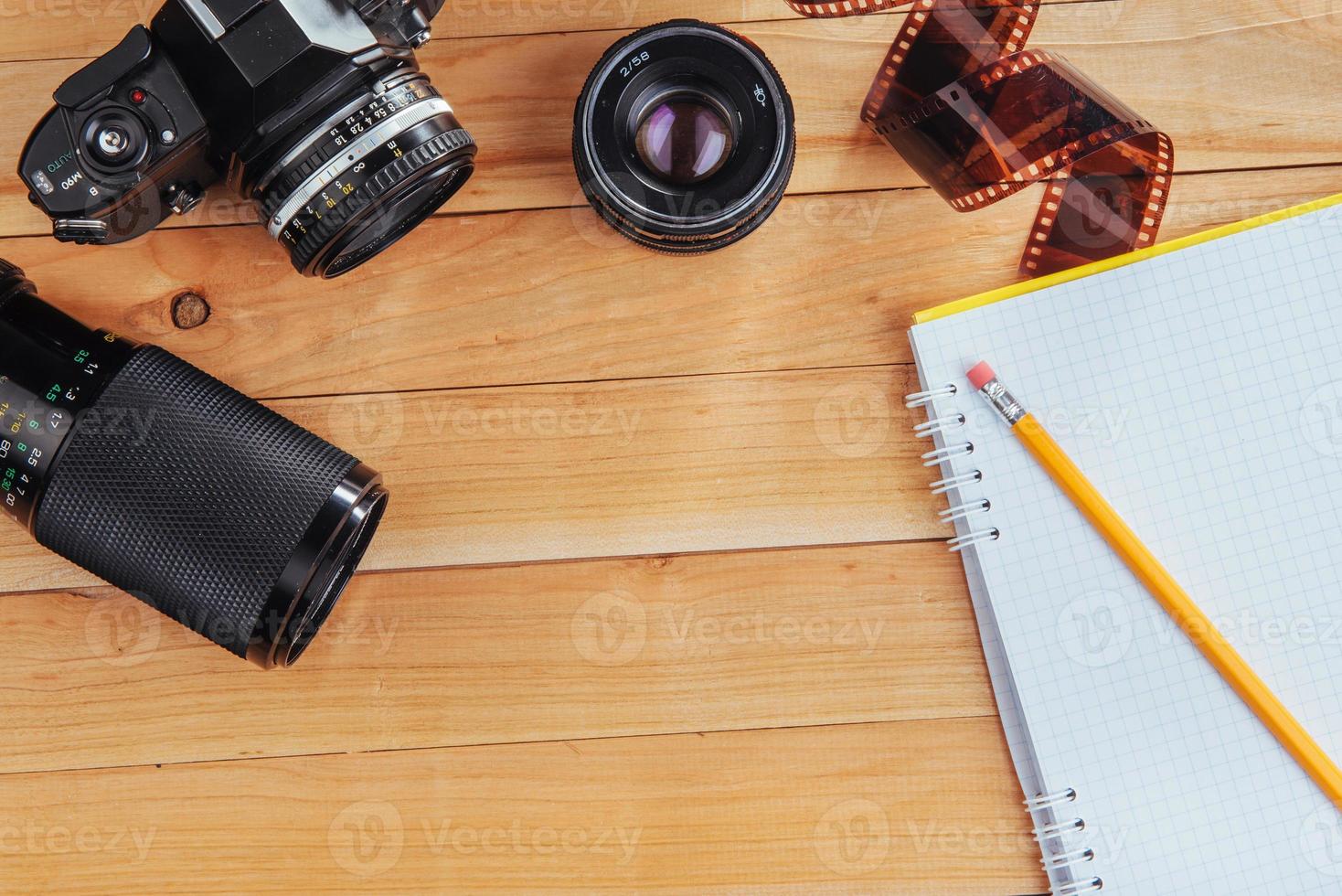 la vieja cámara de cine y rollo de película y cuaderno con lápiz sobre un fondo de madera foto