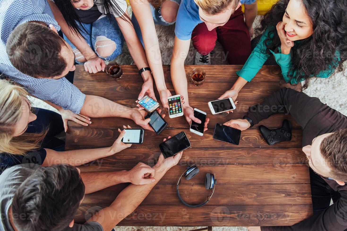 Top view hands circle using phone in cafe - Multiracial friends mobile addicted interior scene from above - Wifi connected people in bar table meeting - Concept of teamwork photo