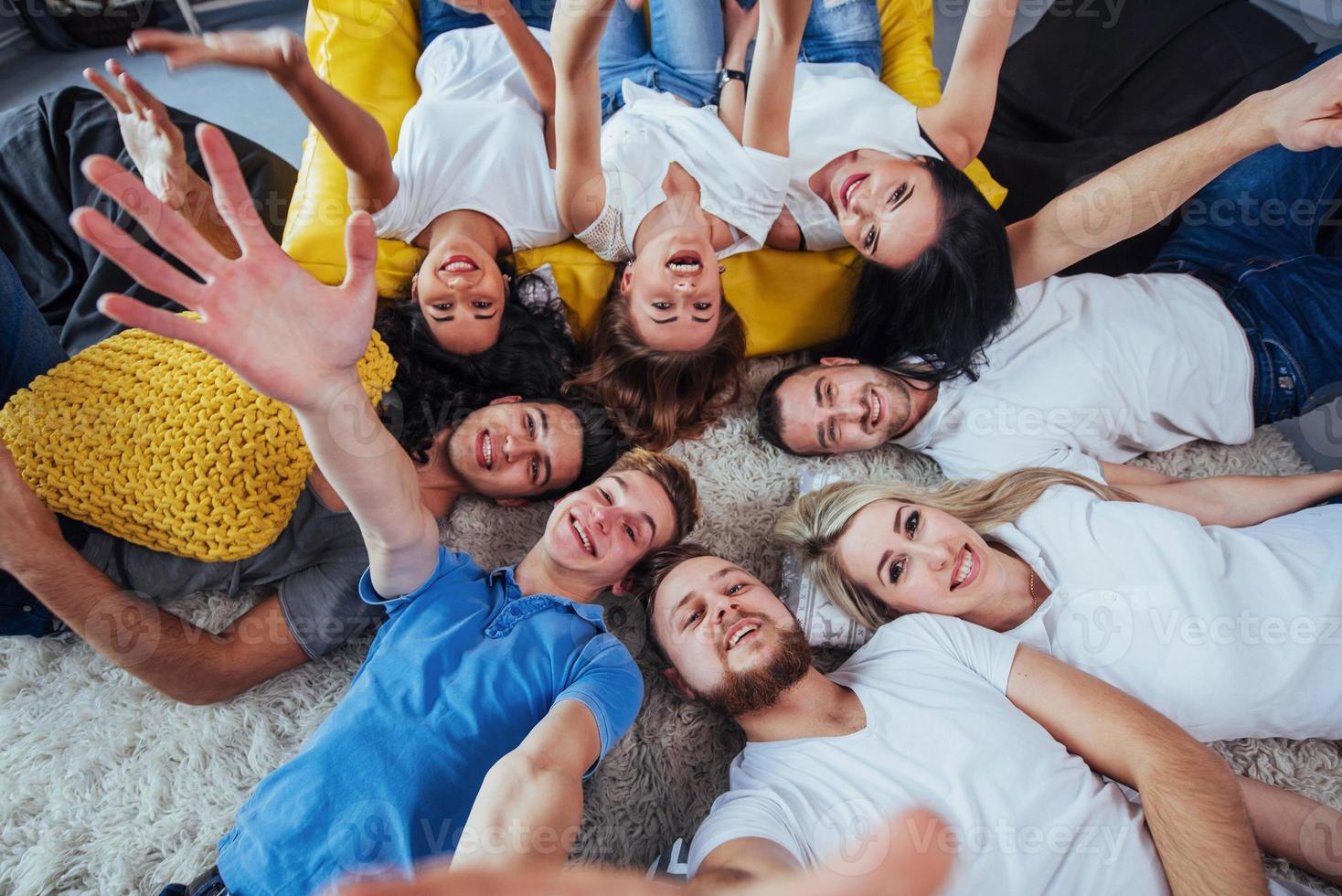 grupo de jóvenes hermosos haciendo selfie tirados en el suelo, mejores amigos niñas y niños juntos divirtiéndose, planteando un concepto de estilo de vida emocional foto