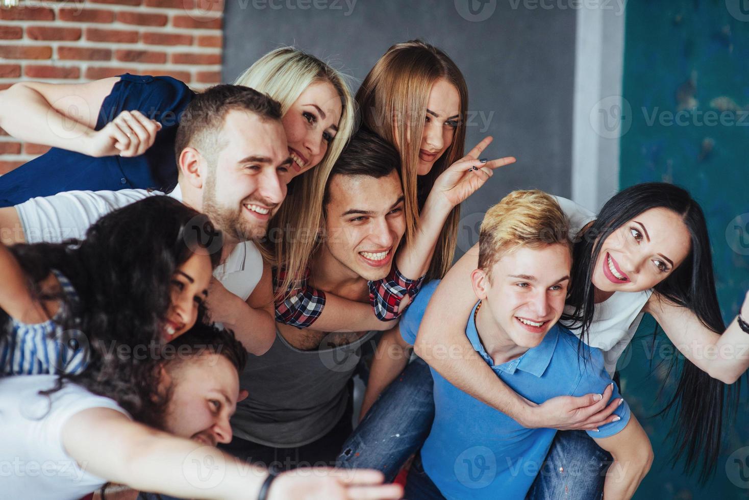 Group portrait of multi-ethnic boys and girls with colorful fashionable clothes holding friend  posing on a brick wall, Urban style people having fun, Concepts about youth  togetherness lifestyle photo