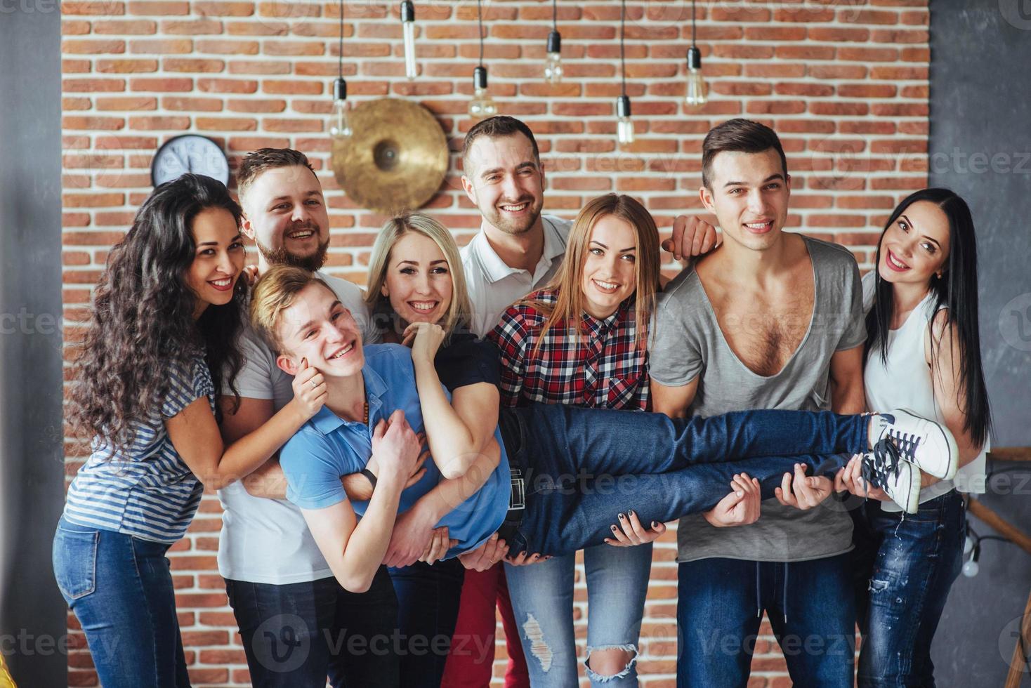 Group portrait of multi-ethnic boys and girls with colorful fashionable clothes holding friend  posing on a brick wall, Urban style people having fun, Concepts about youth  togetherness lifestyle photo