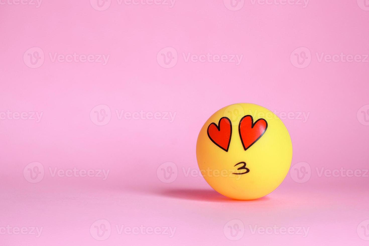 Love on face emoticon with mouth kissing isolated on pink background with copy space photo