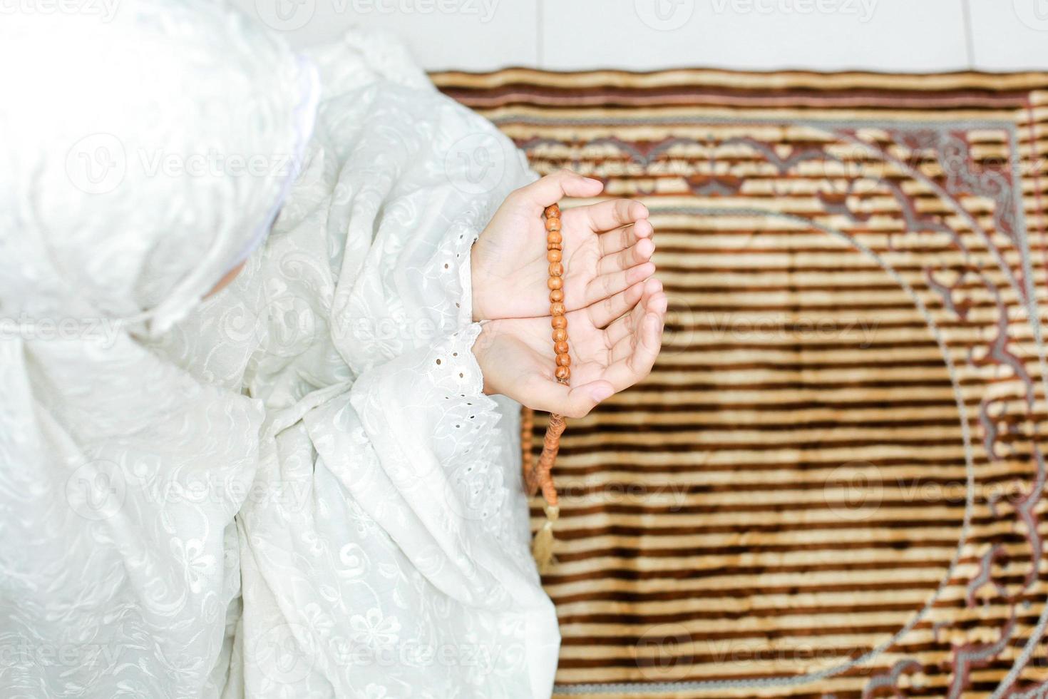 vista superior de la mano de una mujer musulmana con un gesto suplicante rezando a allah mientras sostiene cuentas de rosario foto