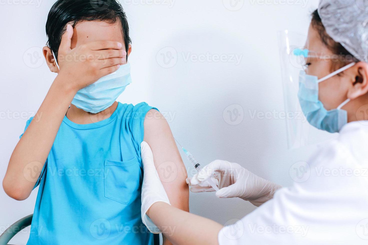 Scary boy expression  when being in vaccine injection by the doctor, injections phobia. Medicine, vaccination, immunization and health care concept photo