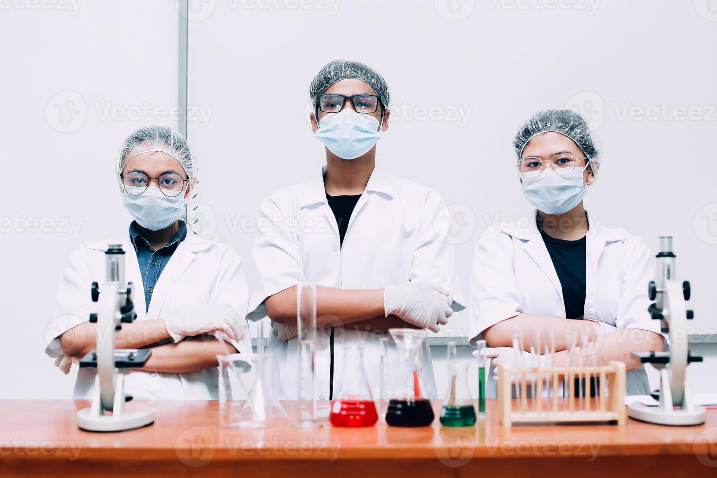 Group of scientist wearing protective mask and uniform posing with confidence photo