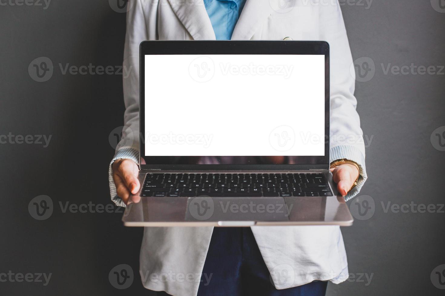 Cropped shot of business woman holding blank screen laptop while standing isolated on grey background photo