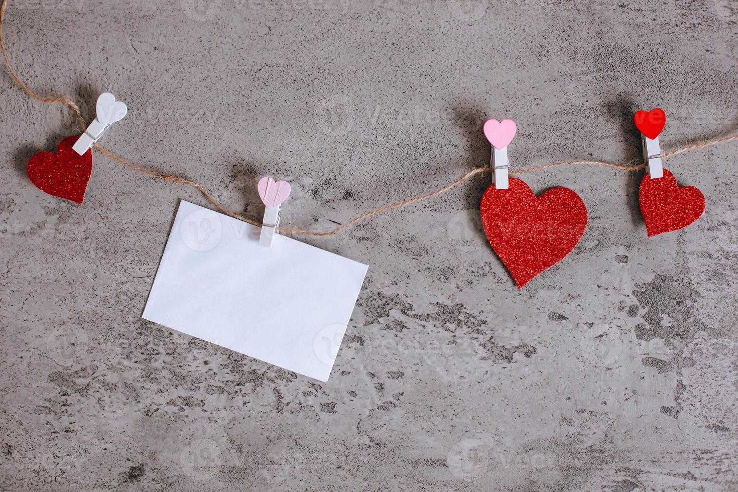 White envelope and heart shape paper pinched on clothes line rope photo