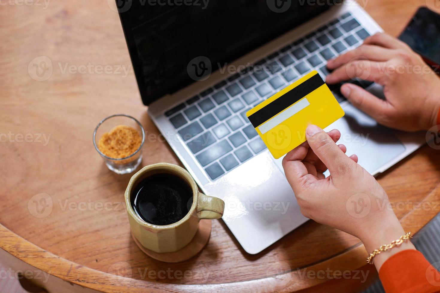 manos sosteniendo una tarjeta de crédito y usando una computadora portátil para el pago de compras en línea foto