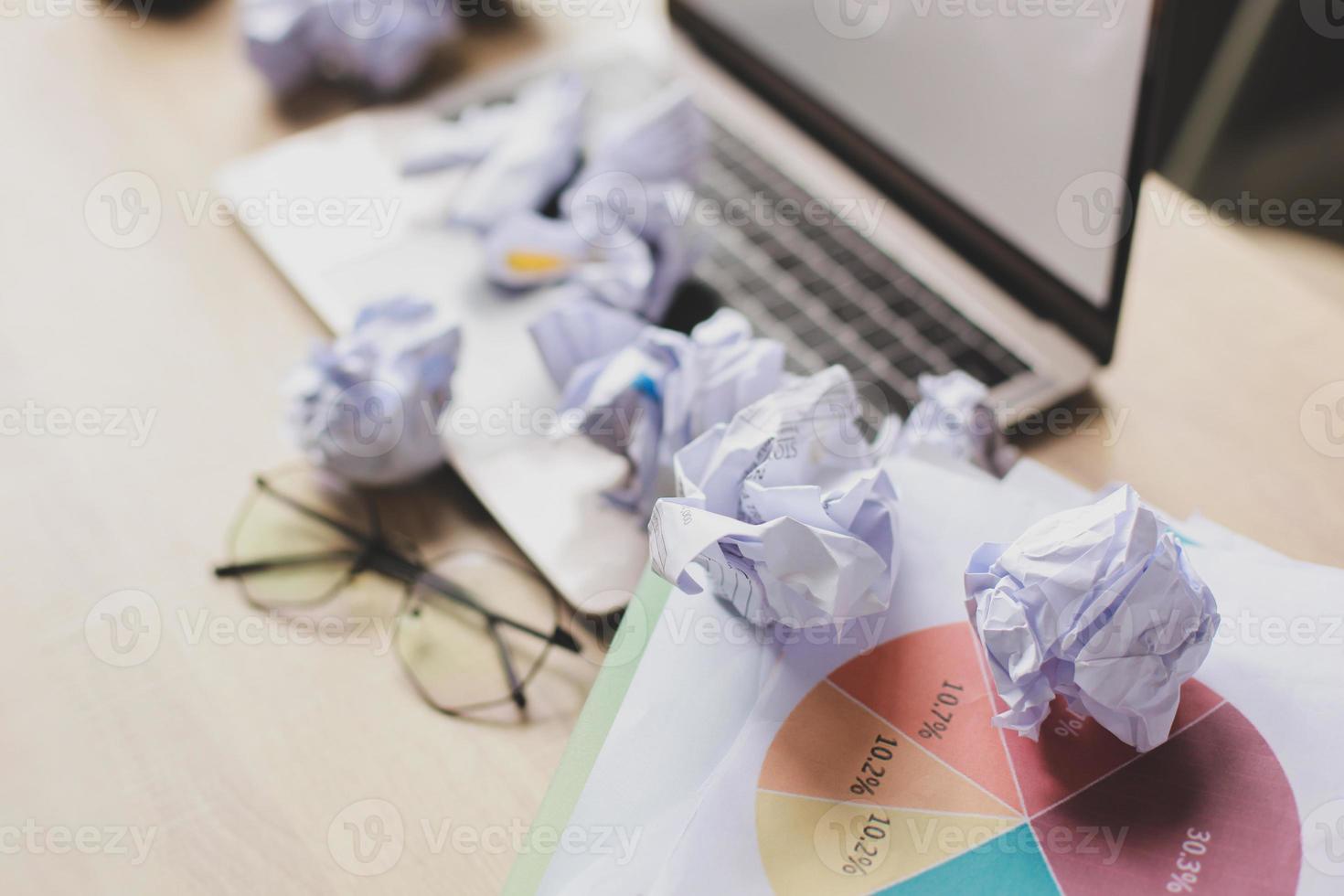 muchas bolas de papel arrugadas en la desordenada mesa de la oficina. foto