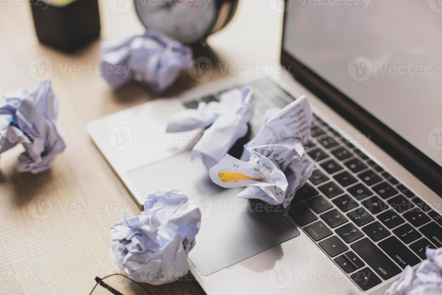 muchas bolas de papel arrugadas en la desordenada mesa de la oficina. concepto de creatividad empresarial foto