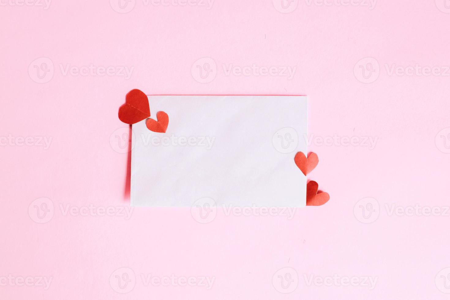 White envelope with mini heart shape on pink background photo