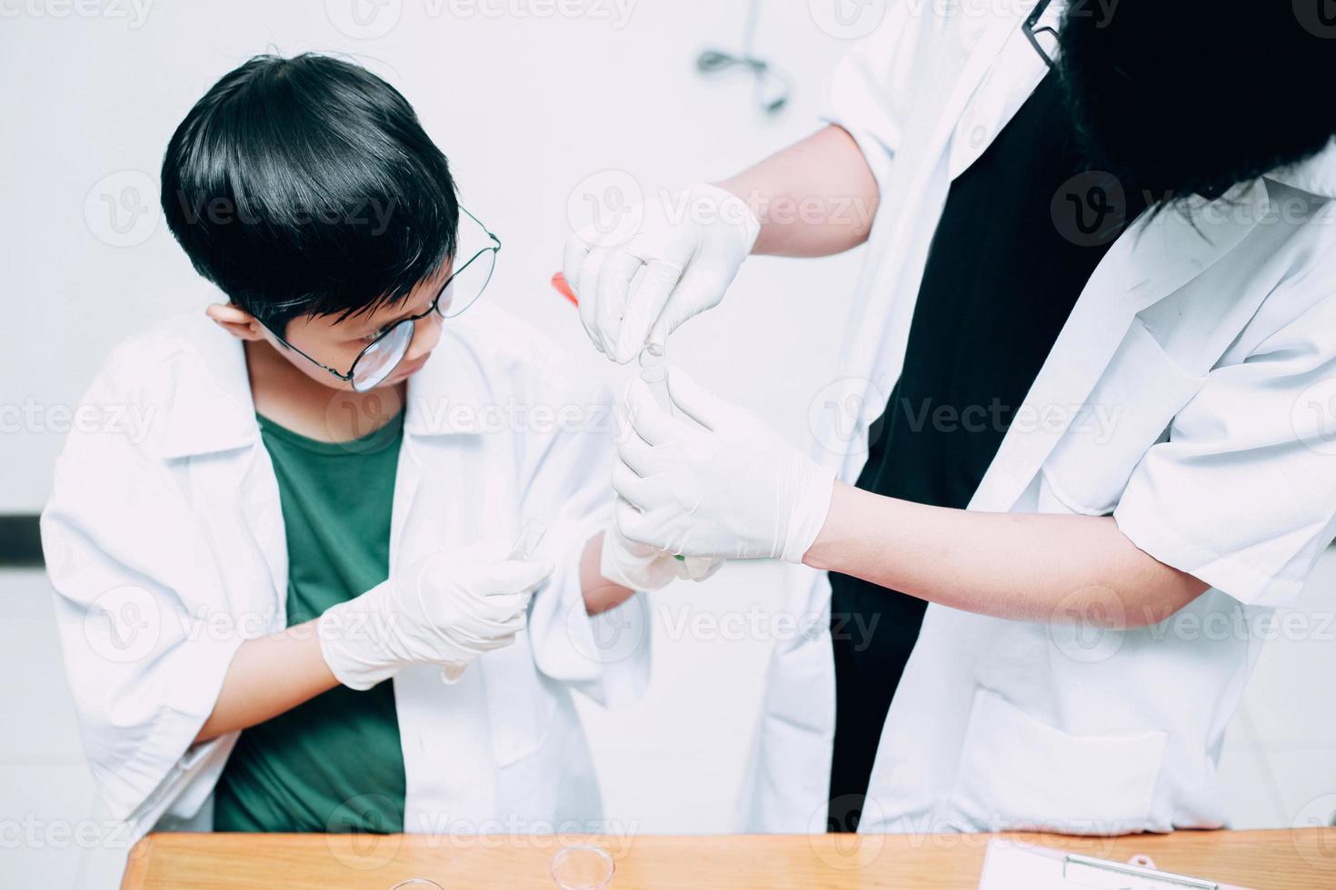 un niño estudiante que estudia química con un profesor en el laboratorio. día nacional de la ciencia, día mundial de la ciencia foto
