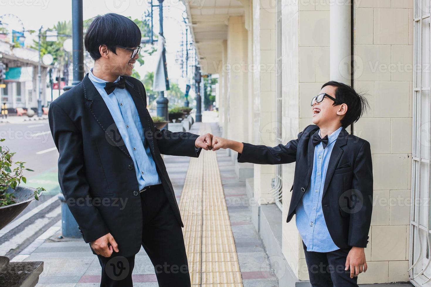 Portrait of a two joyful teenager with vintage suit outfit doing a fist bump photo