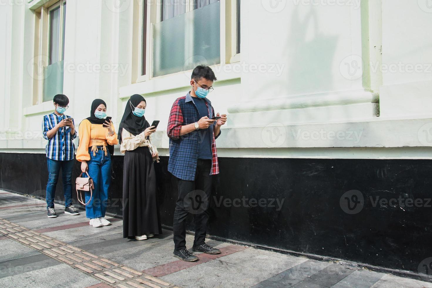 Group of young people in a row keeping social distancing against the diffusion of the coronavirus or covid-19 pandemic disease. New normal concept. photo