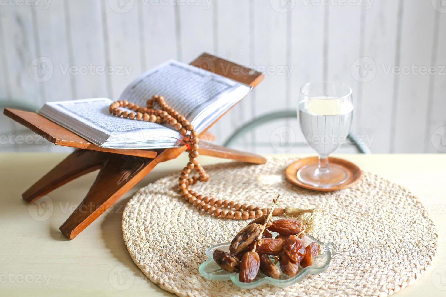Kurma or dates fruit with glass of water, holy Quran and prayer beads on the table. Traditional Ramadan, iftar meal. Ramadan kareem fasting month concept photo