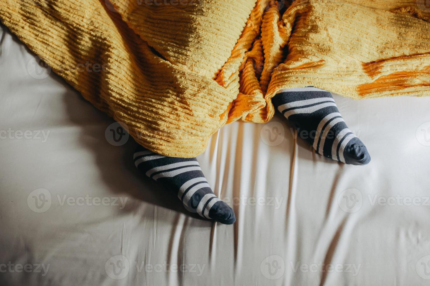 Feet in warm socks under the blankets on the bed photo