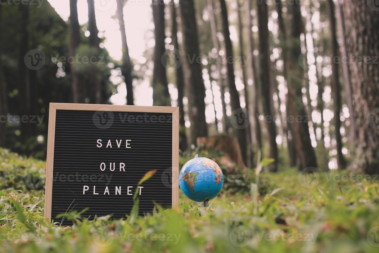 Quote on letter board says Save Our Planet with earth globe with forest background, earth day concept photo