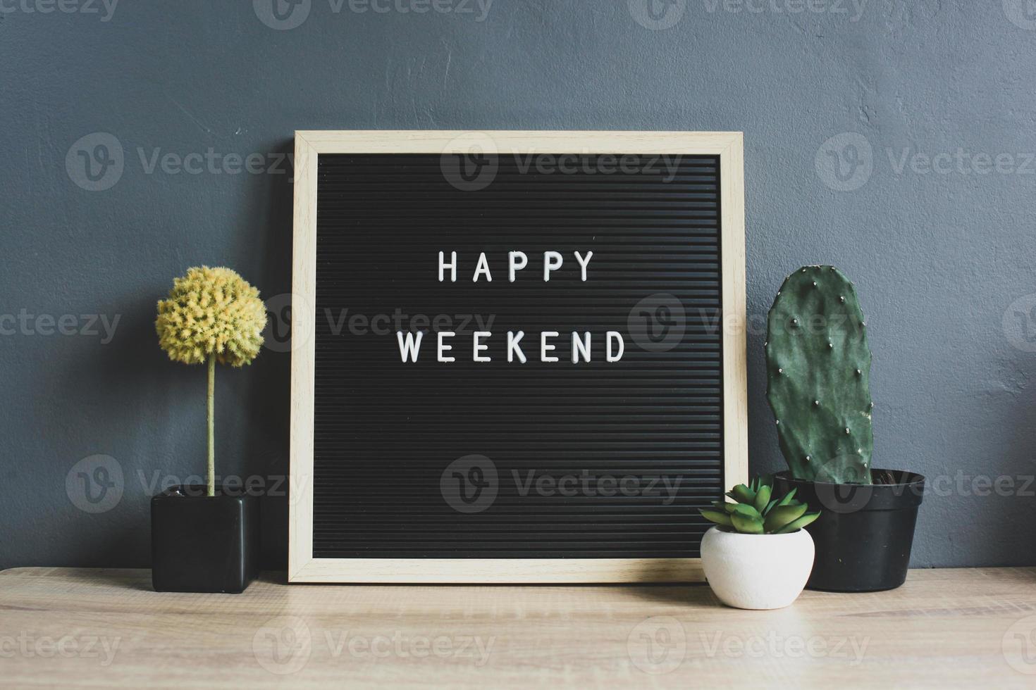 HAPPY WEEKEND quote on blackboard with cactus, succulent and decorative plant on wooden table photo