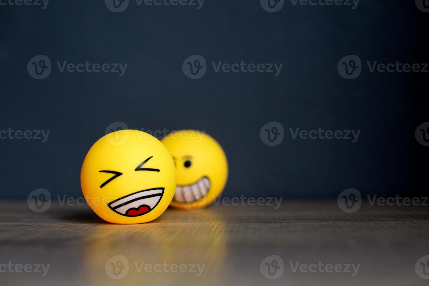 Laugh emoticon with blurry smiley emoticon isolated on black background. Selective focus and copy space photo