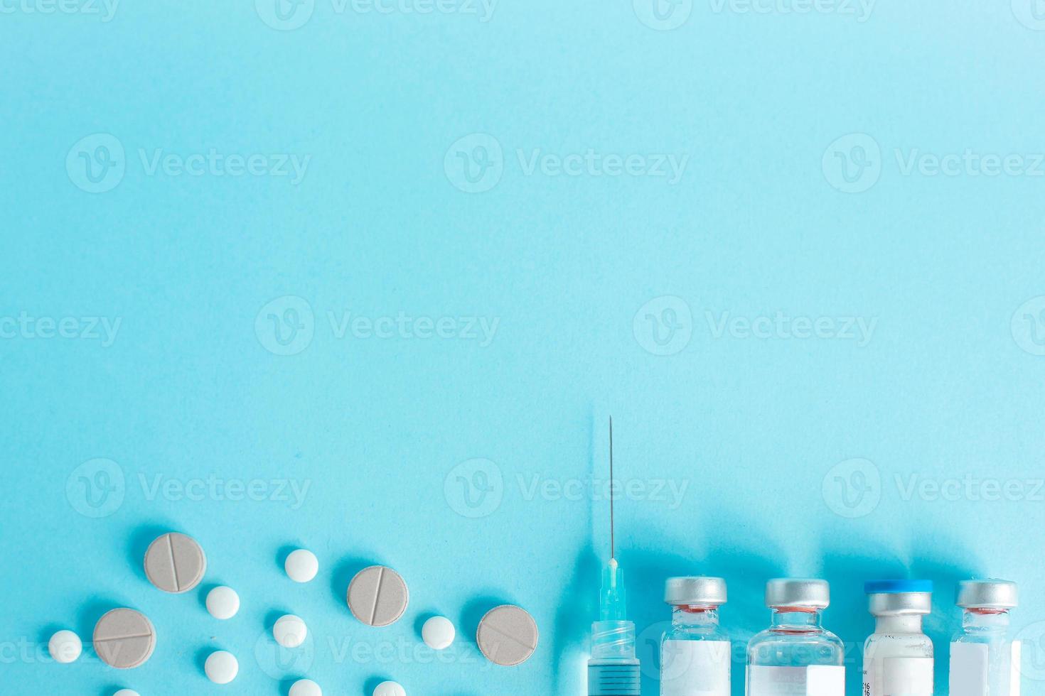 Syringe and vial drug with round tablet as a border on a blue background with copy space photo