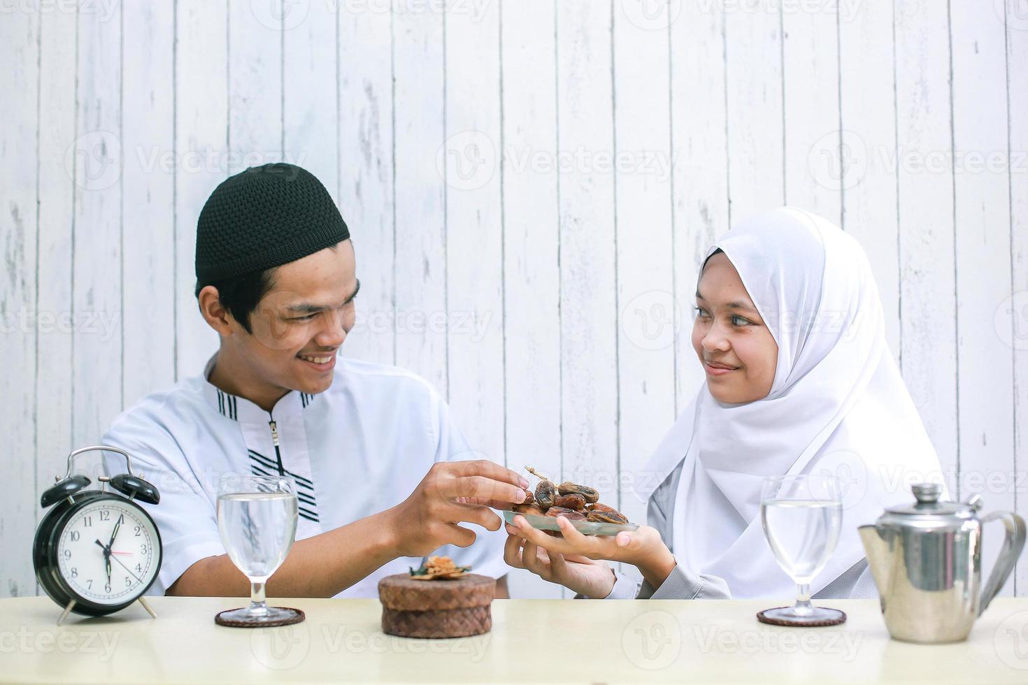 joven pareja musulmana en tiempo de iftar. mujer musulmana dando fechas al hombre musulmán. Ramadán tradicional, comida iftar. concepto de mes de ayuno ramadan kareem foto