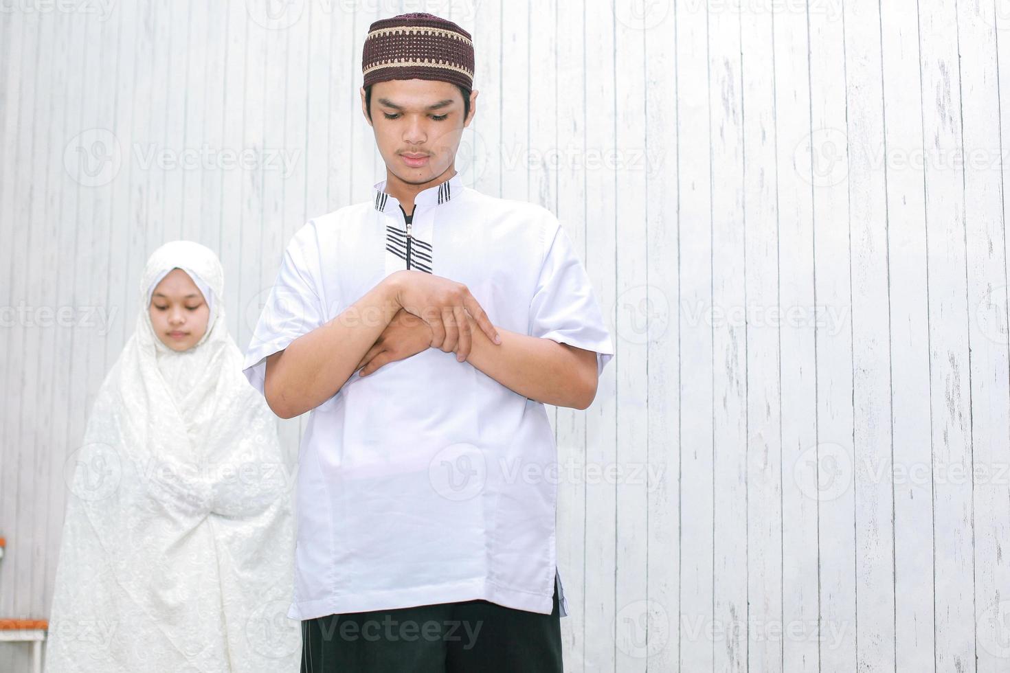 pareja joven musulmana con la mano en el pecho están haciendo salat juntos foto