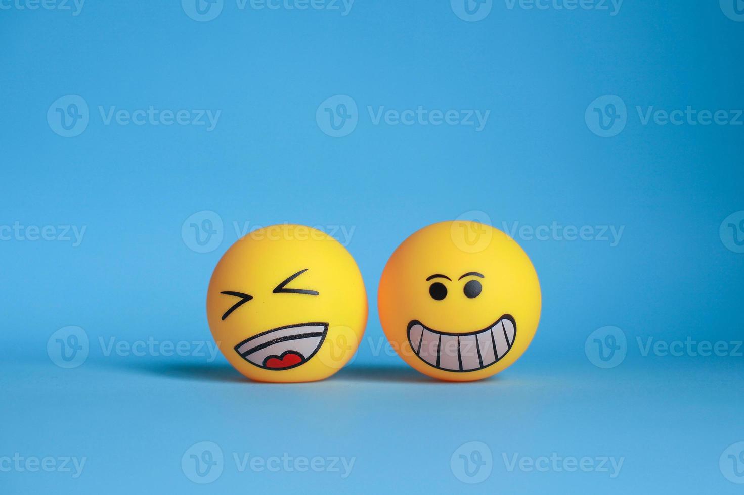 Smiley emoticon with laugh emoticon isolated on blue background photo