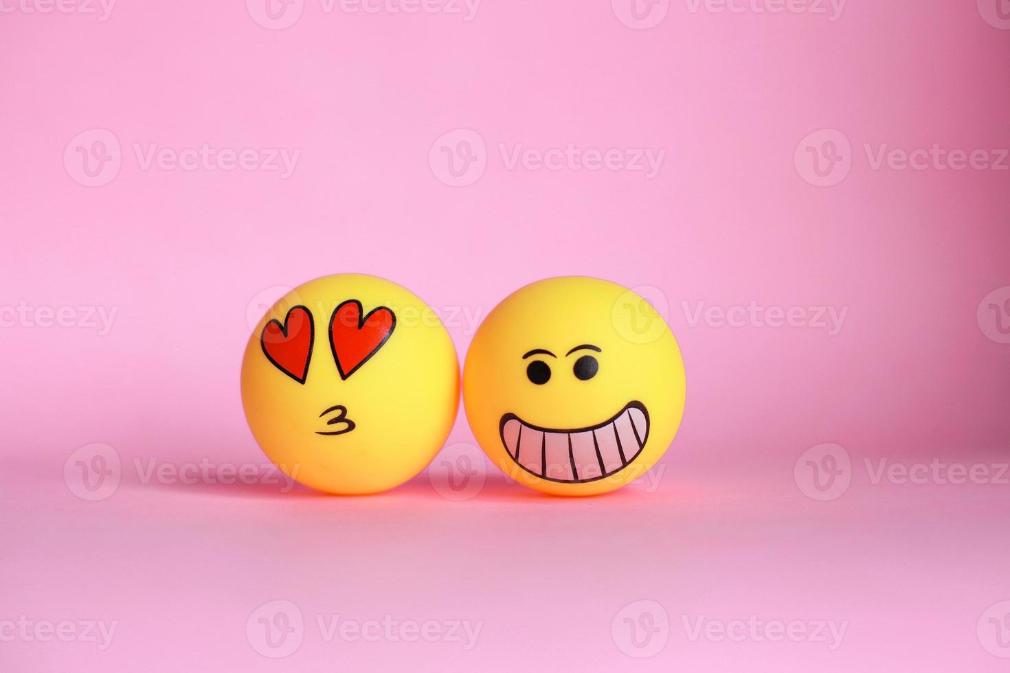 emoticono sonriente y amor en la cara emoticono con besos en la boca aislado sobre fondo rosa. foto