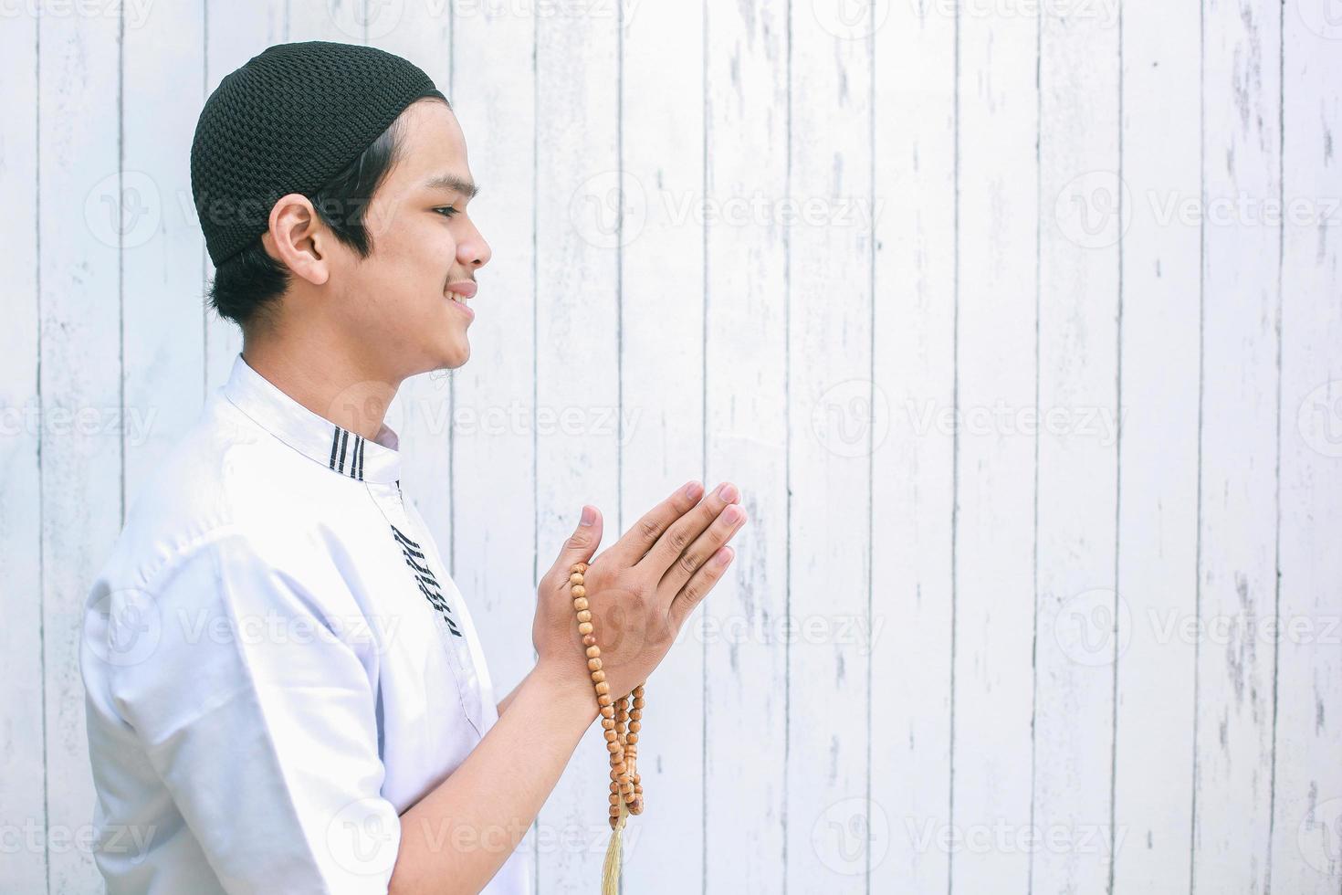 Asian muslim man wearing koko holding prayer beads doing muslim handshake for welcoming guests or greeting on Eid Mubarak, Eid Fitr, Eid Al-Fitr celebration with copy space photo