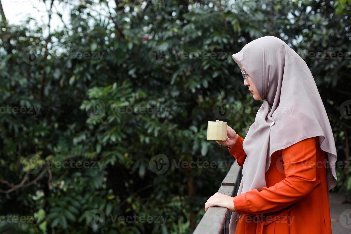 mujer musulmana sosteniendo una taza de café en el balcón de su casa foto