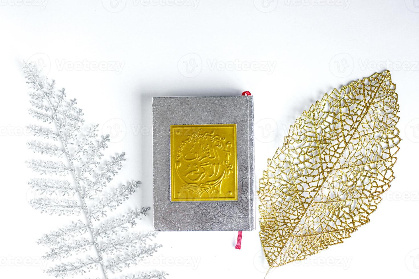 Gold Arabic on book of holy Quran with silver and gold leaves on white background, Bandung Indonesia, March 2021 photo