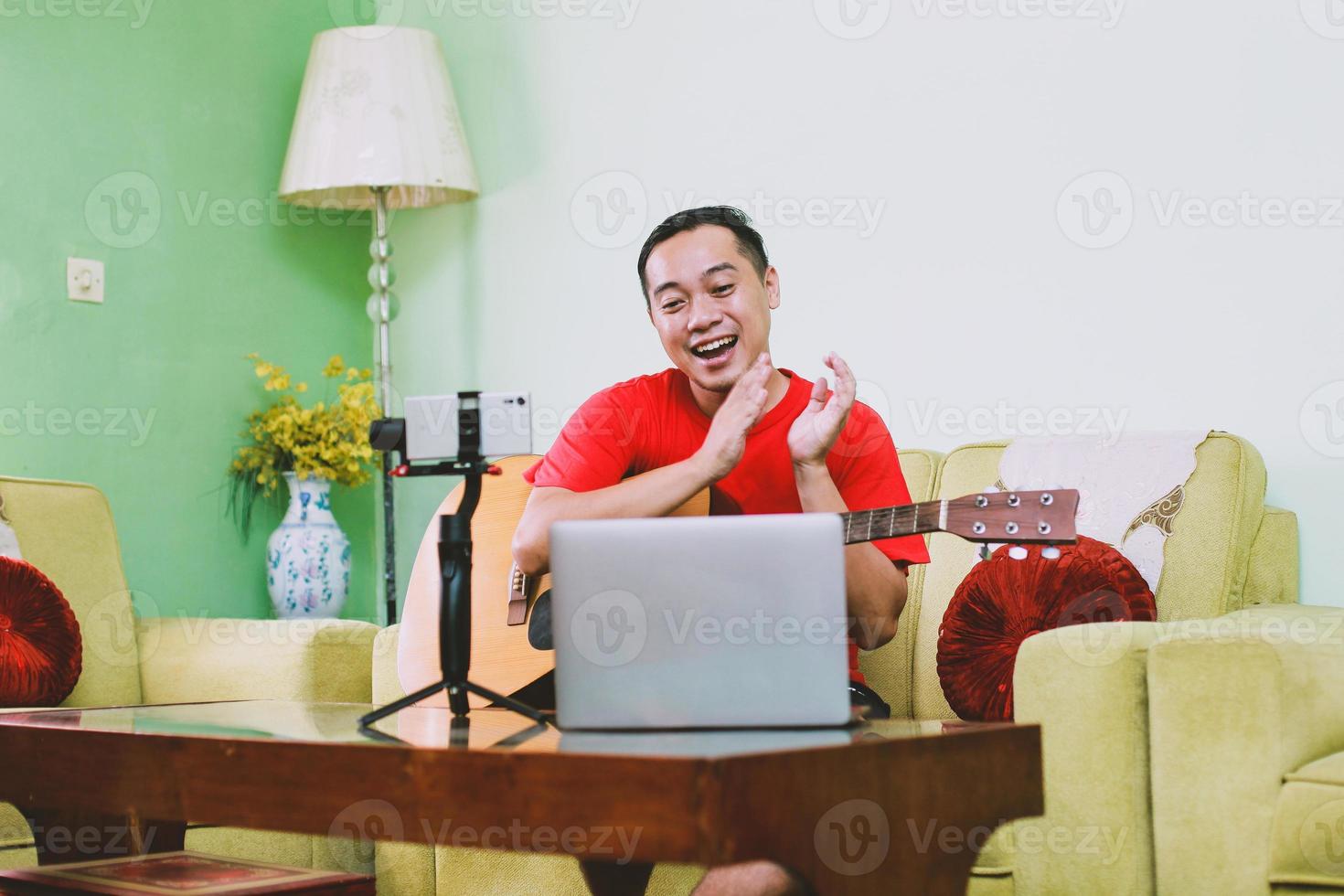 Happy asian youtuber or musician interacting with the audience by giving applause during live streaming on a laptop at home photo