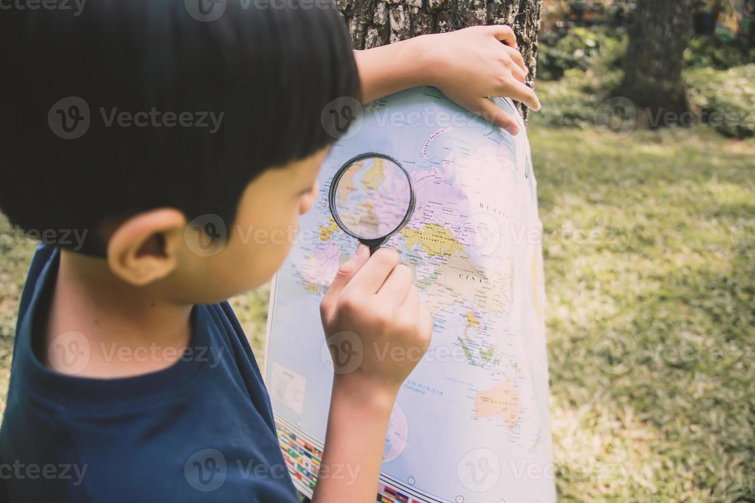 un niño buscando ubicación en el mapa mundial usando una lupa foto
