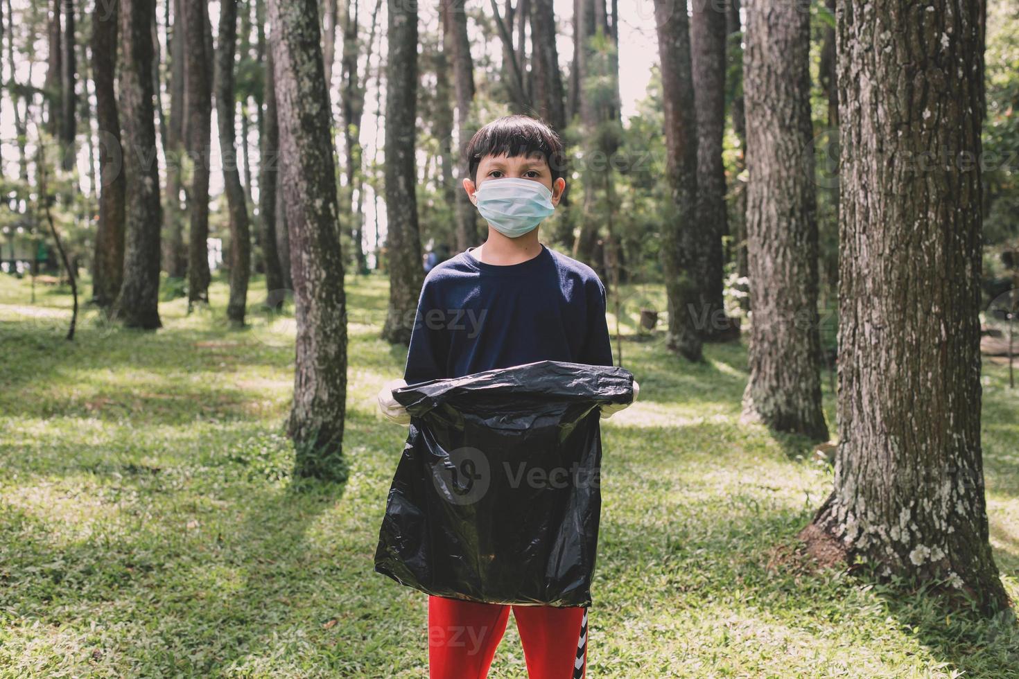 un niño asiático que sostiene una bolsa de basura se prepara para recoger basura foto