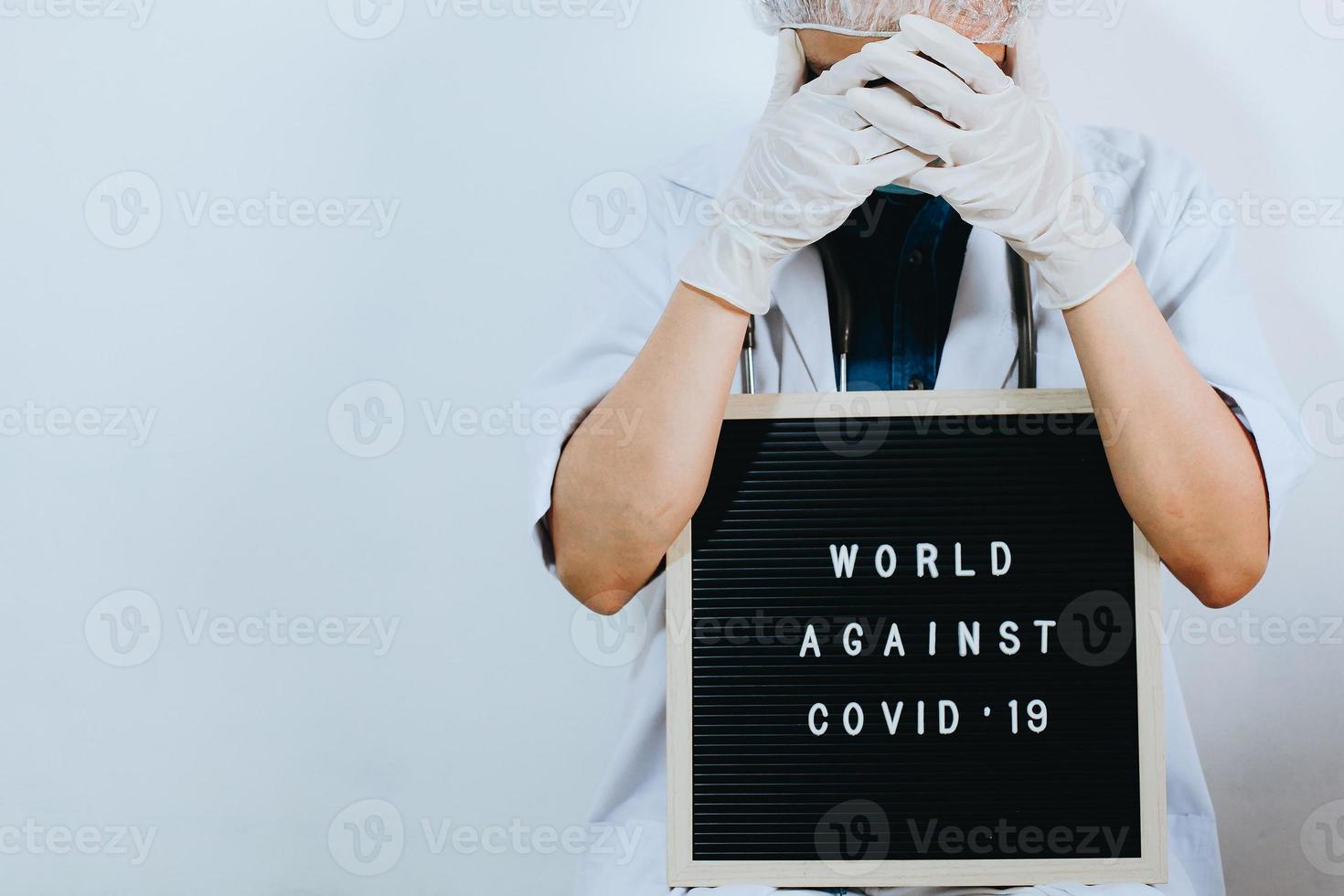 Cropped shot of doctor are covering her face with quote on letter board says World Against Covid 19 isolated on white background. Campaign against coronavirus with copy space photo