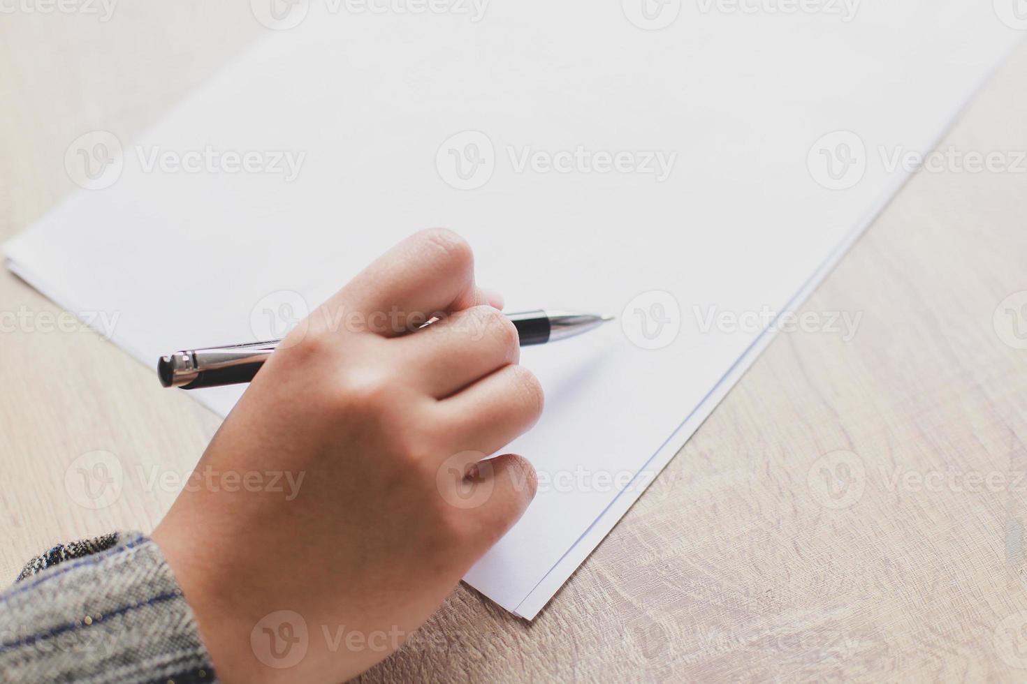 Close up of woman's hands writing in paper placed on wooden desk with copy space. Concept for education and business. Make plans and lists photo