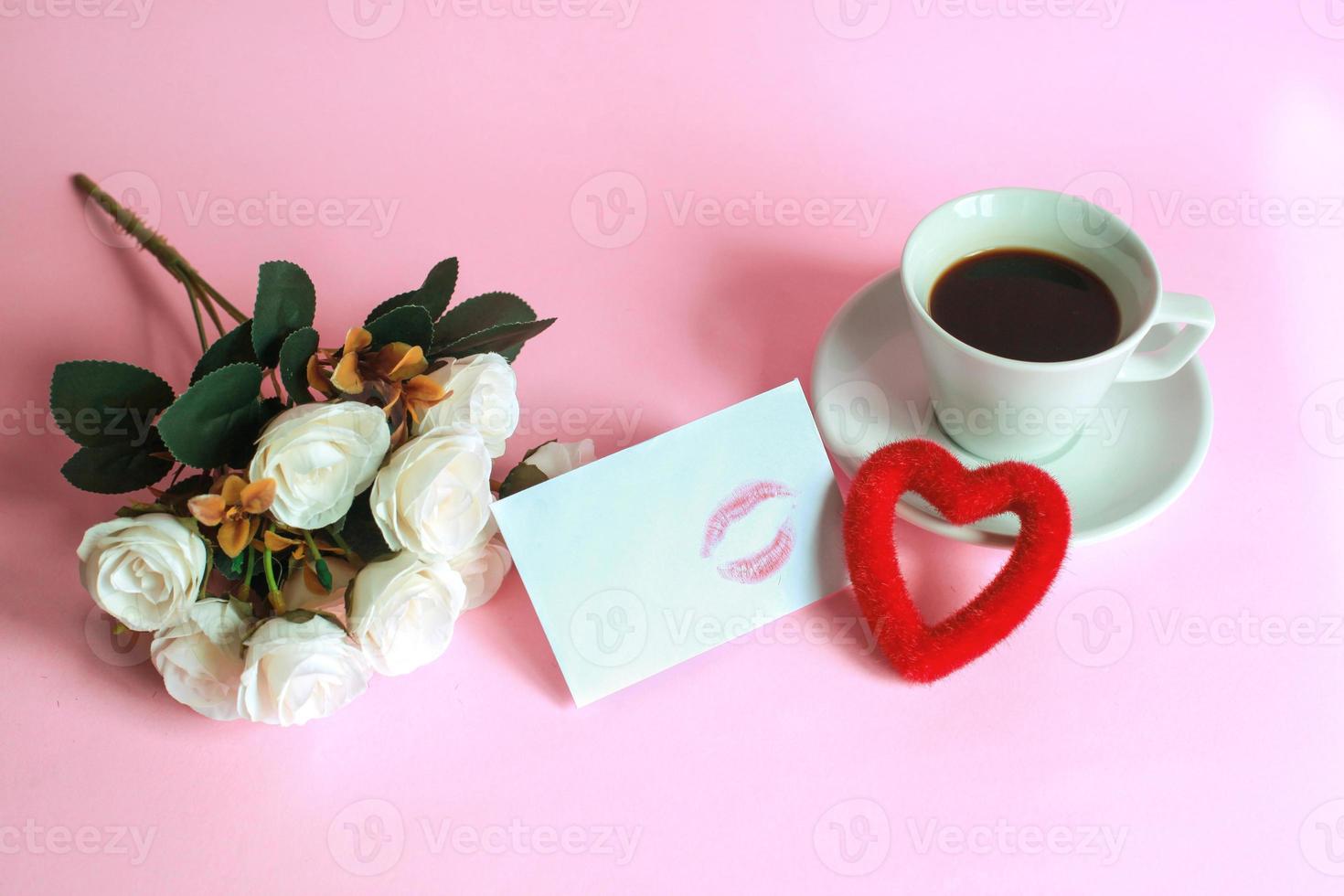 Cup of coffee with rose, kiss marked on white envelope and heart shape isolated on pink background photo