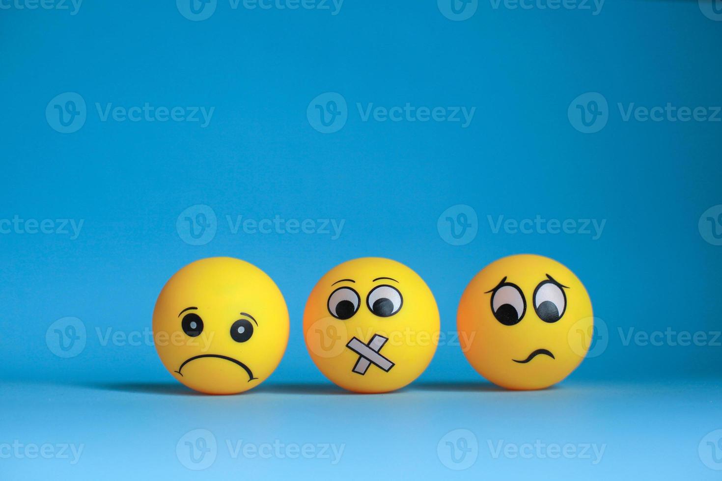 Sad emoticon with silent face emoticon and confused emoticon on blue background photo