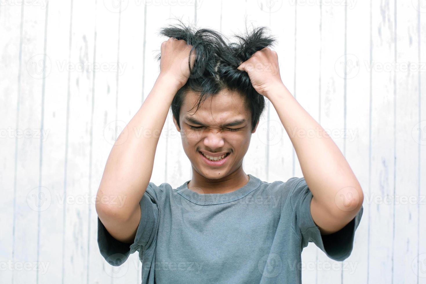 People, stress, tension and migraine concept. Upset unhappy young asian man squeezing head with hands, suffering from headache. photo