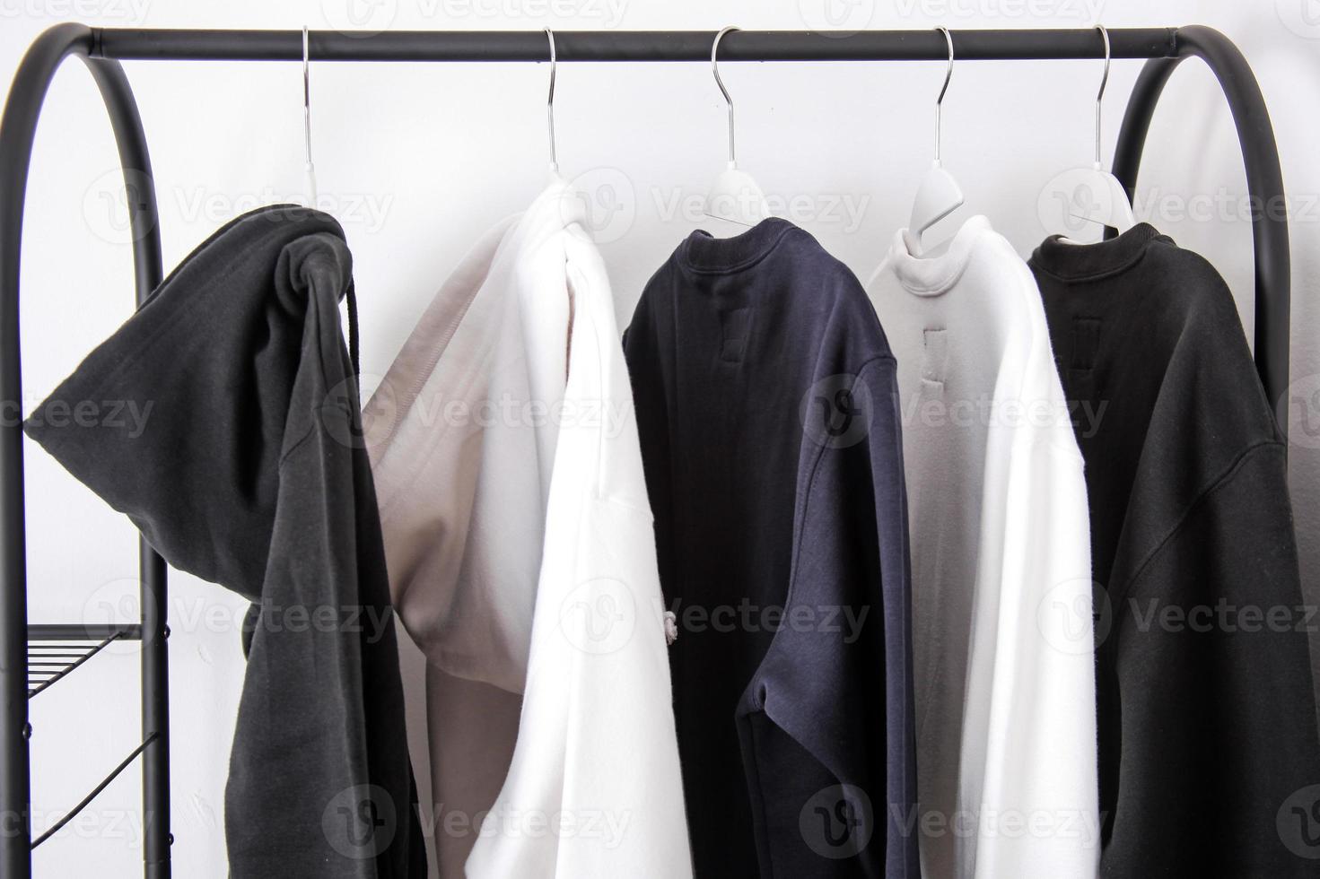 Various outwear such as hoodie and sweater hanging on hanger clothes photo