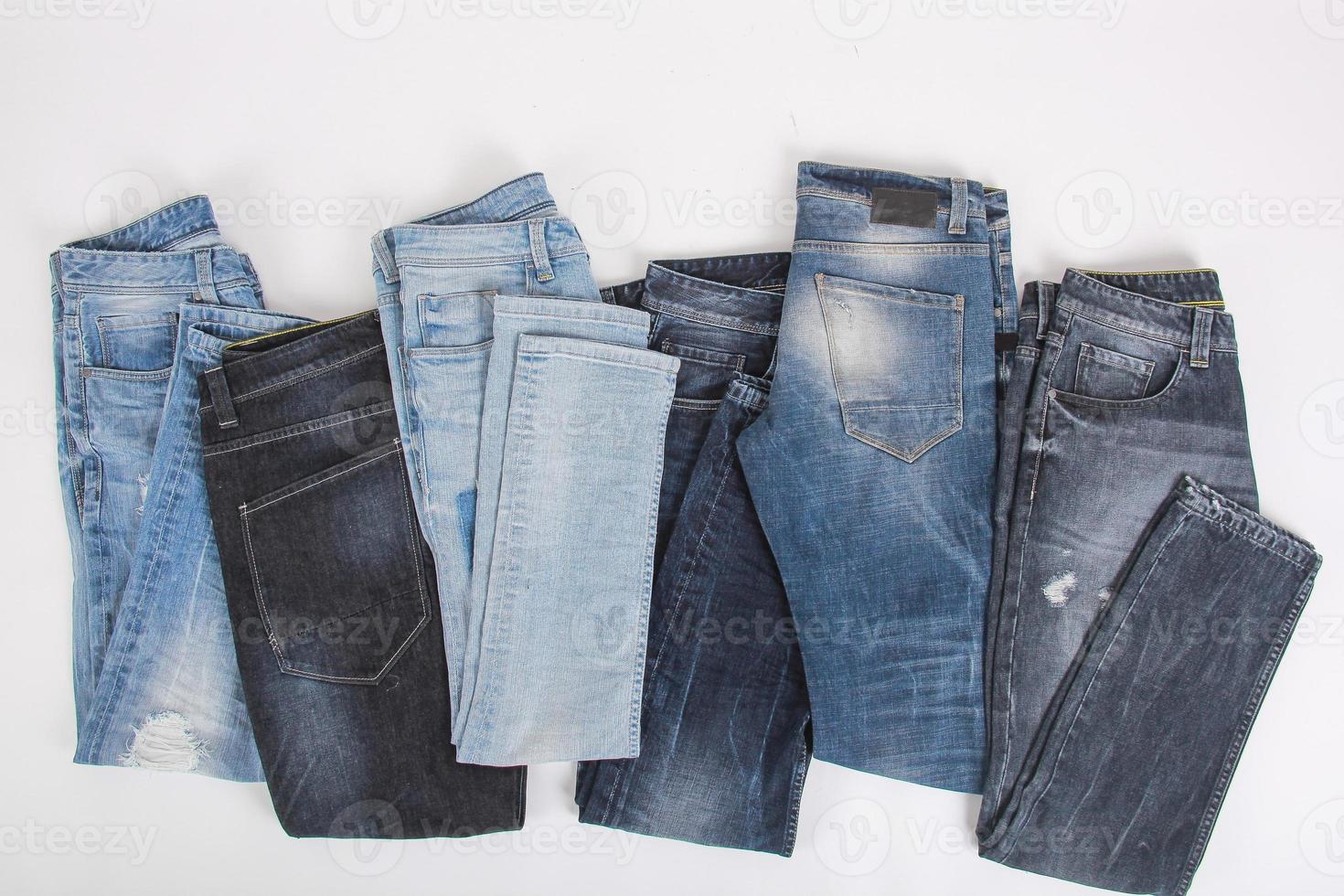 Various folded denim pants isolated on white photo