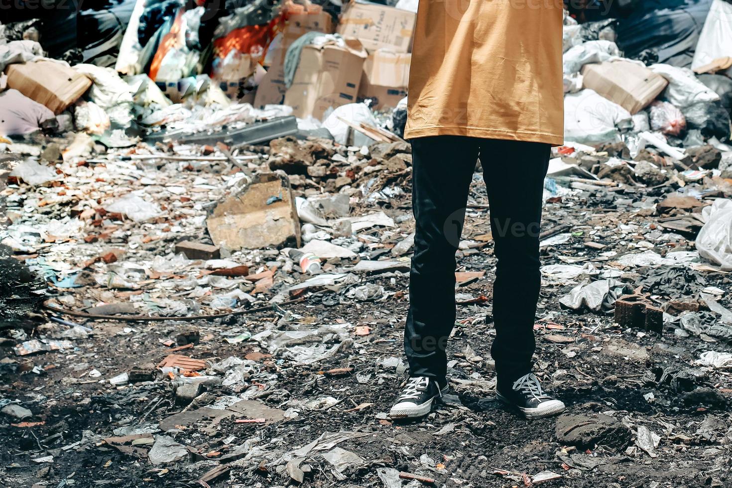 A man standing in trash dump or landfill with messy garbage dump pile on background photo