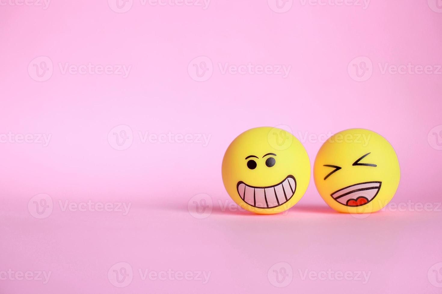 Smiley emoticon with laugh emoticon isolated on pink background with copy space photo