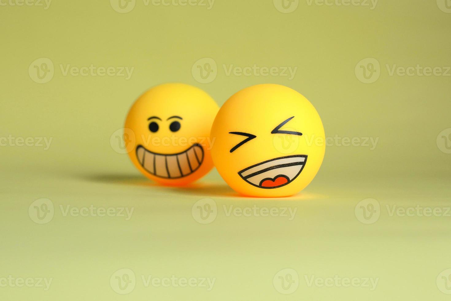 Laugh emoticon with blurry smiley emoticon isolated on yellow background. Selective focus photo