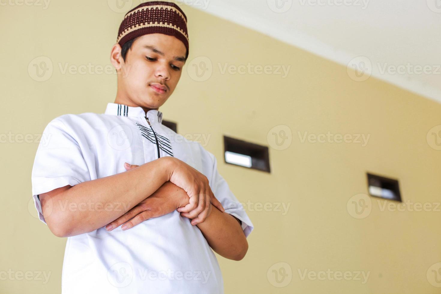 Young asian muslim man stands with hand in chest are doing salat photo