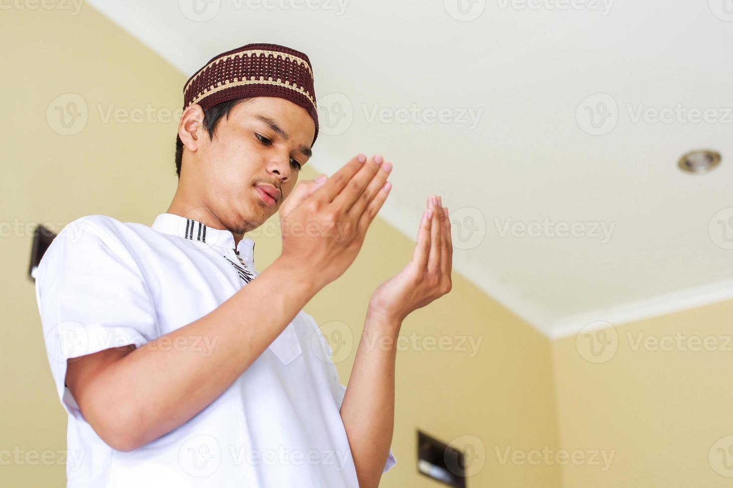 Young asian muslim man with praying hand, praying to god photo