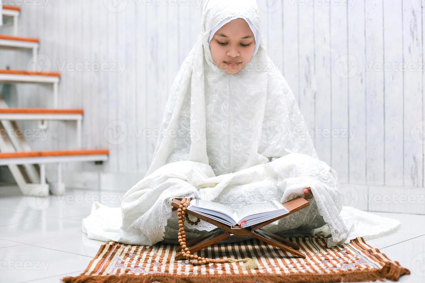 Religious young asian muslim are reading the holy book Al-Quran on the prayer mat at home. photo