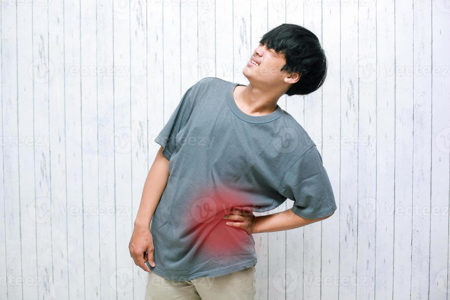 joven asiático sosteniendo su dolor de espalda, el concepto de dolor de espalda, ácido láctico en los músculos y problemas de columna, lumbago foto