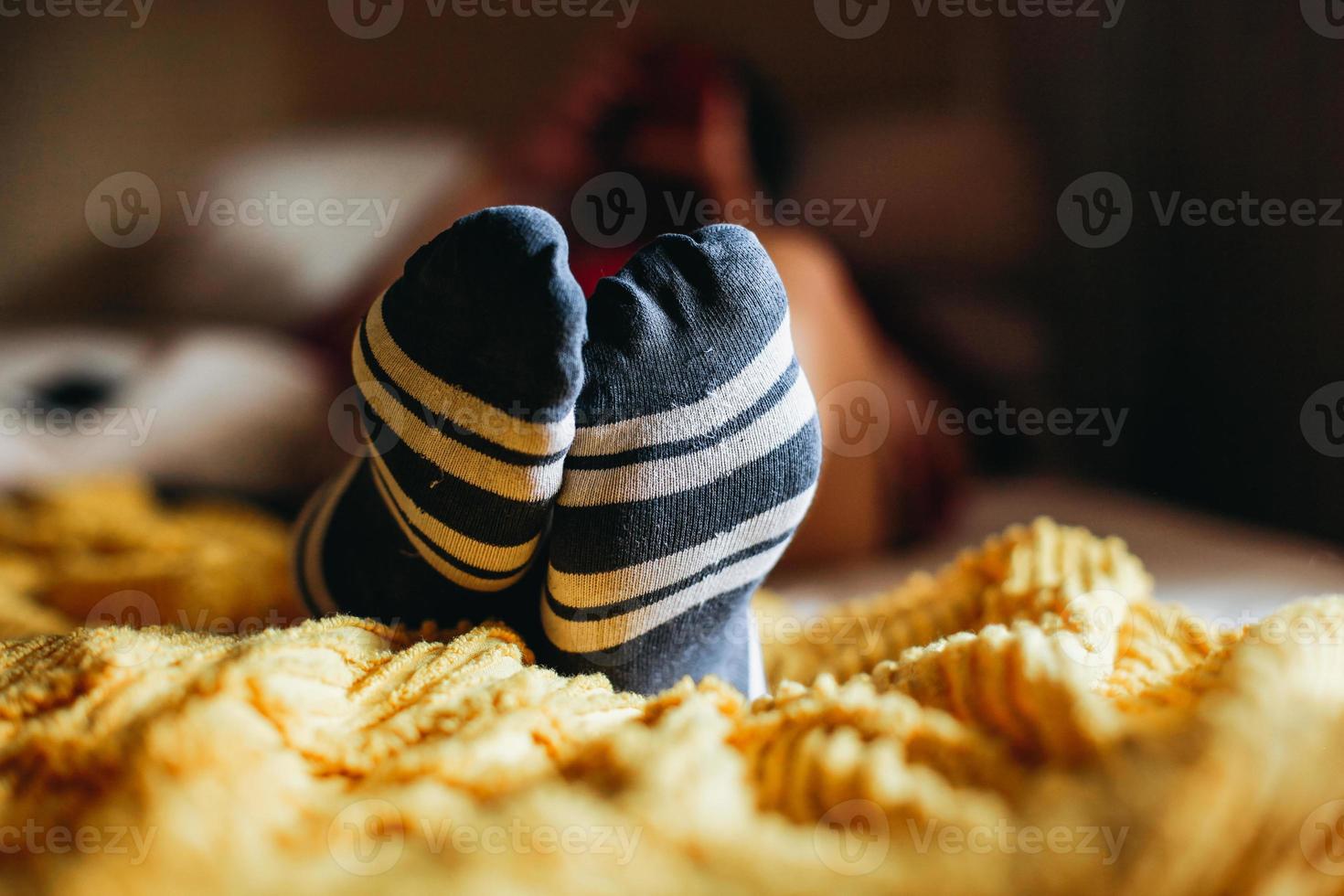 Close up of foot wearing stripes socks on a bed photo