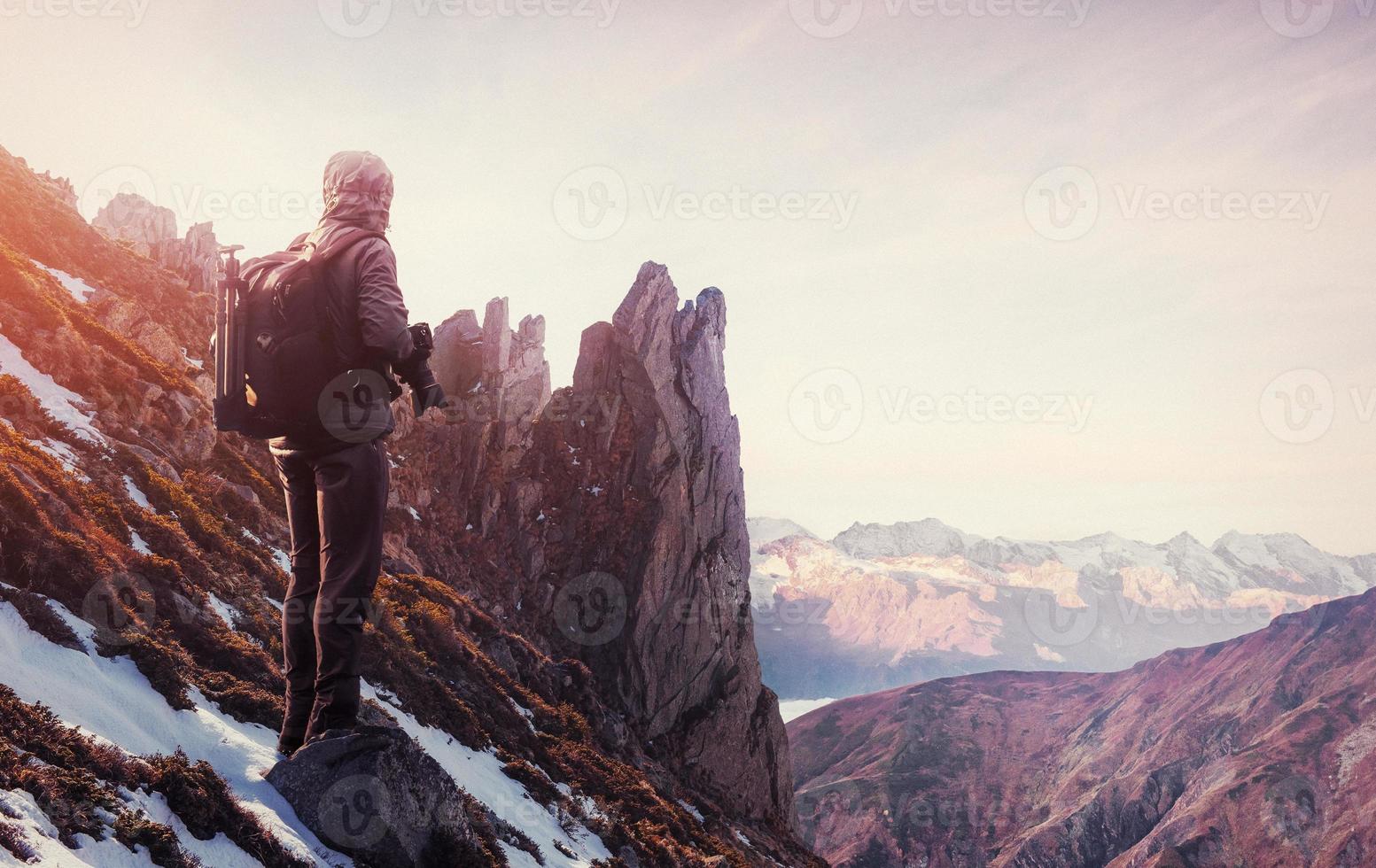 Professional photographer takes photos with big camera on peak of rock